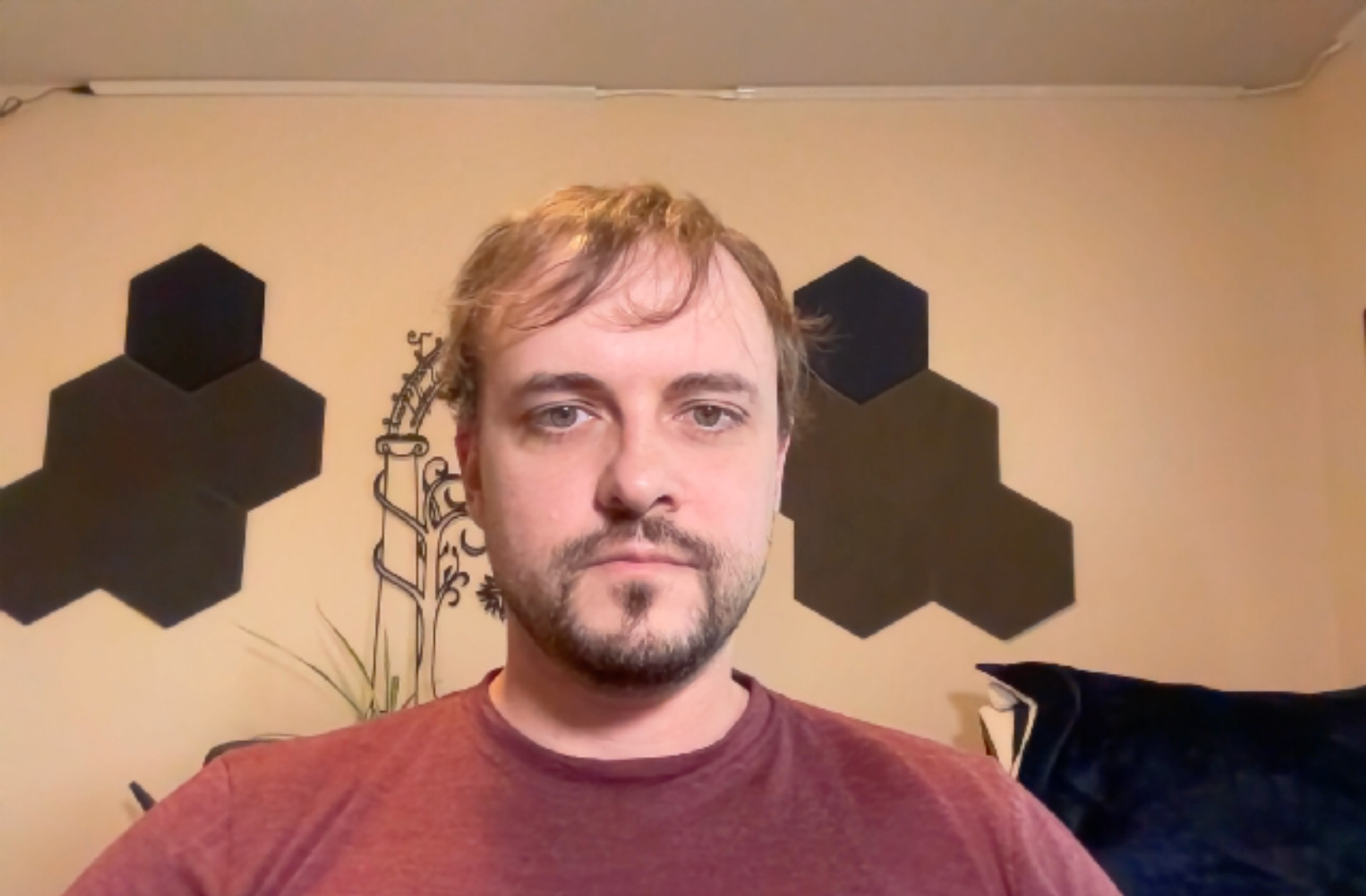 The author in a dimly-lit room. His face is illuminated but the color and quality of the image are much worse than the images from a higher-quality webcam.